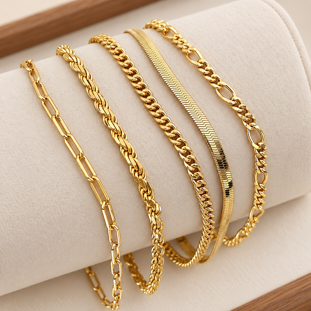 Set de cinco pulseras de cadena doradas, cada una con un eslabón distinto, sobre un soporte de terciopelo crema